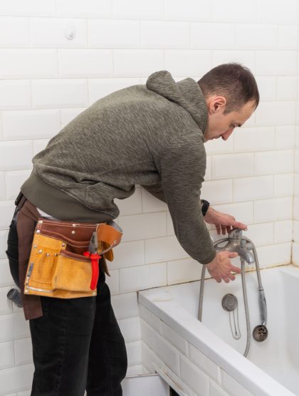 A male plumber with wrench repairs the faucet in the bathroom. replacement and maintenance of plumbing. handyman service. small business. A male plumber with wrench repairs the faucet in the bathroom. replacement and maintenance of plumbing. handyman service. small business. High quality photo